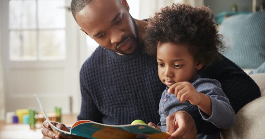 A man reads a book to his young child.