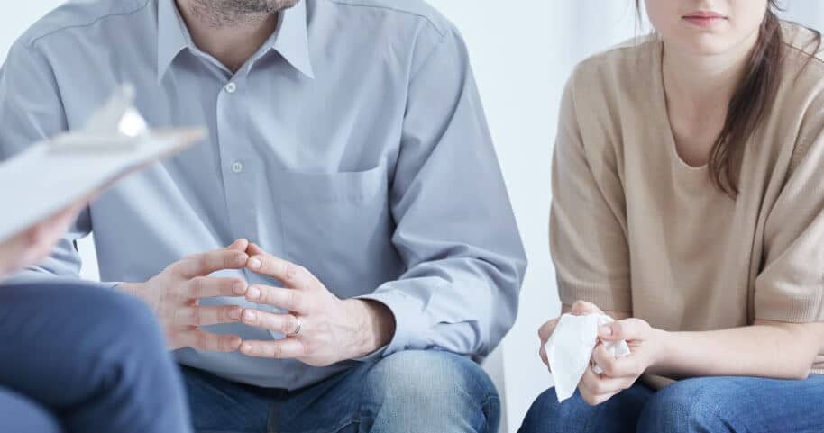 Couple talking to person with clipboard