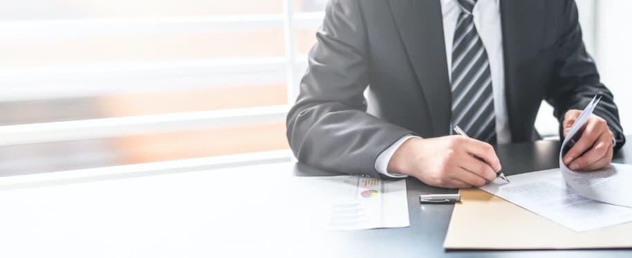 Man in a suit putting pen to paper