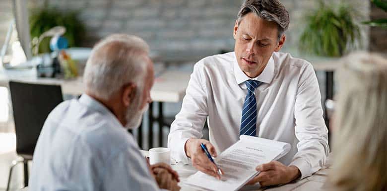 Male attorney pointing to papers for older man to sign