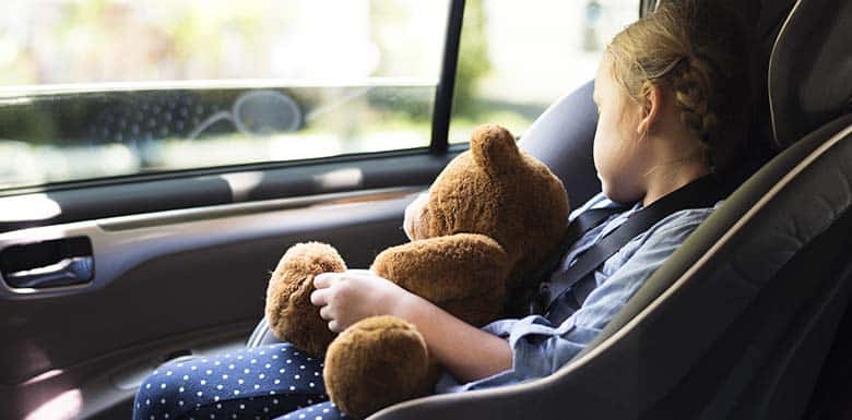 Young child in carseat holding stuffed bear
