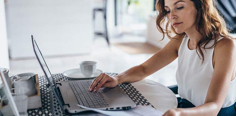 Woman sitting at table with coffee and laptop