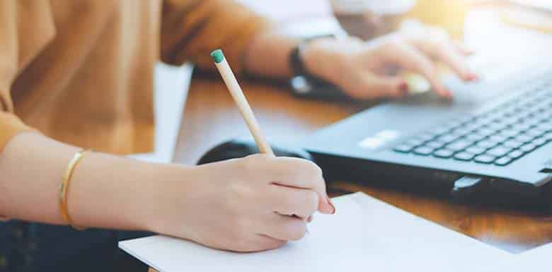 Woman taking notes while researching divorce on computer
