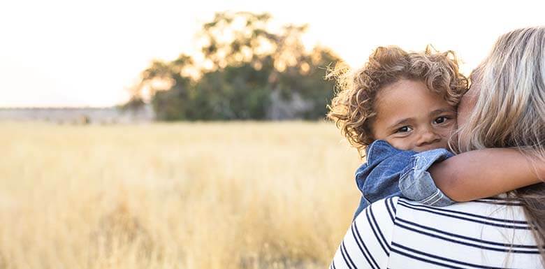Child hugging mother in outdoor field