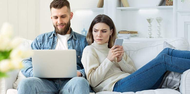 Woman sitting next to spouse and staring at his computer screen