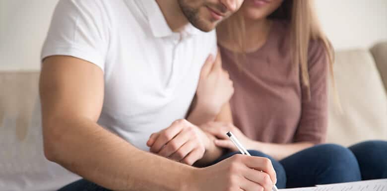 Man and woman looking happy while signing estate planning paperwork