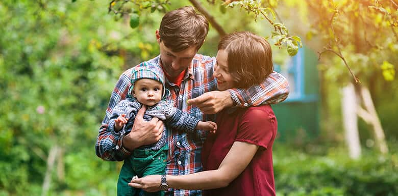Young child being held by father and mother outside on walk