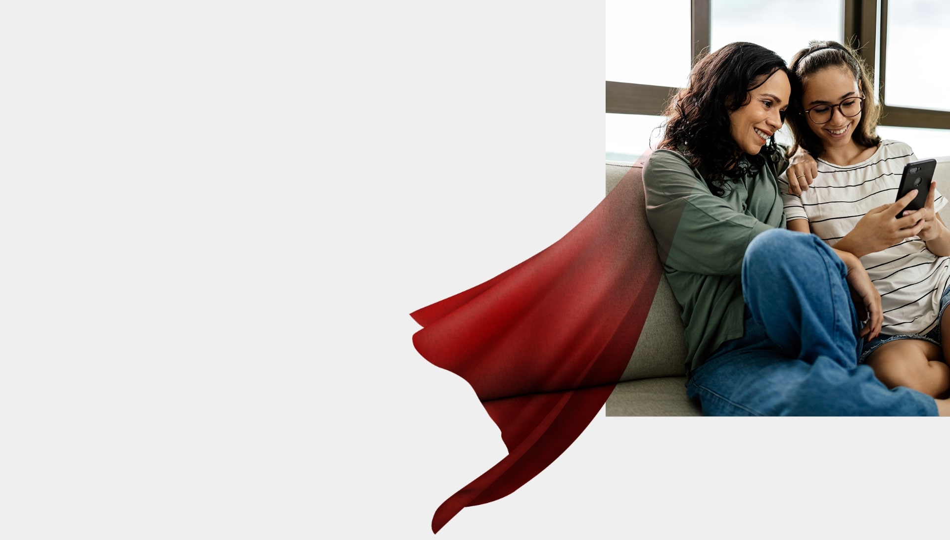 Mother sitting with daughter on couch looking at cellphone together, graphic overlay of hero cape on mother