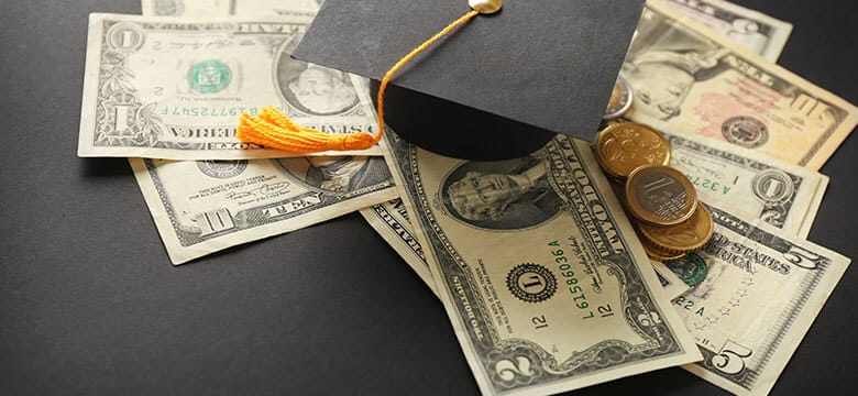 Money on table with graduation hat