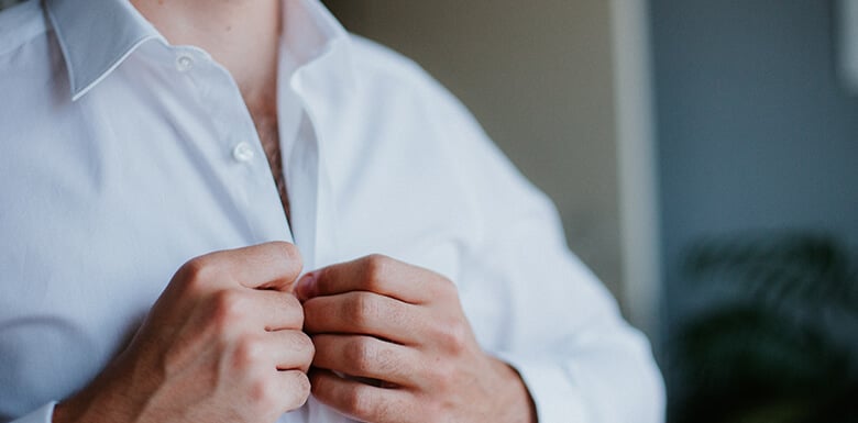 Man buttoning shirt