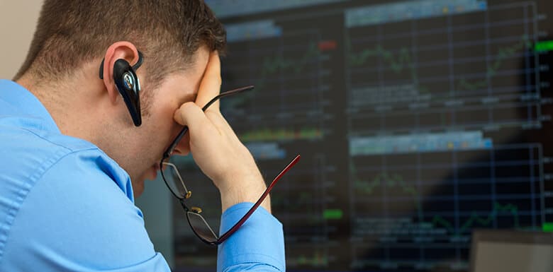 Man upset while looking at stock market data and charts