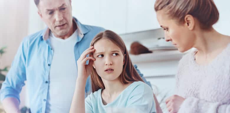 Adolescent daughter looking upset at mom and dad