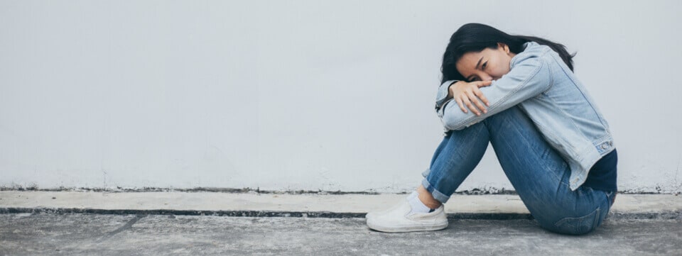 Man sitting alone outside holding her knees