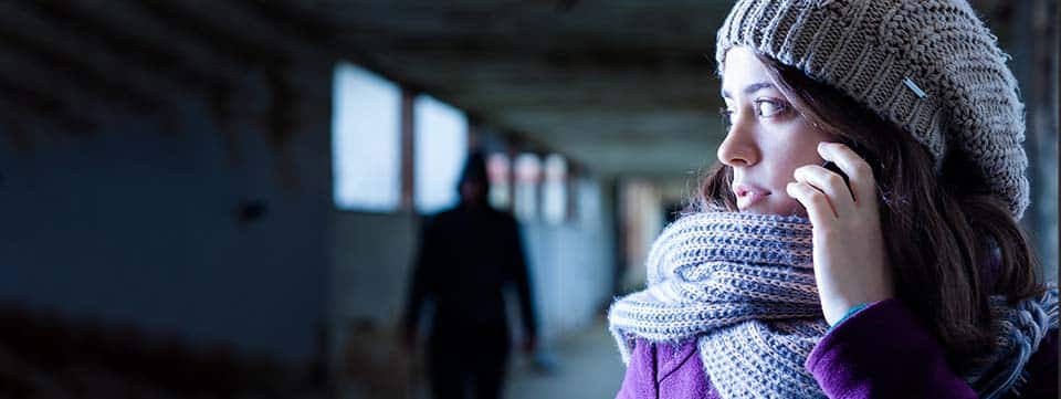 Woman looking fearful over her shoulder in dark hallway