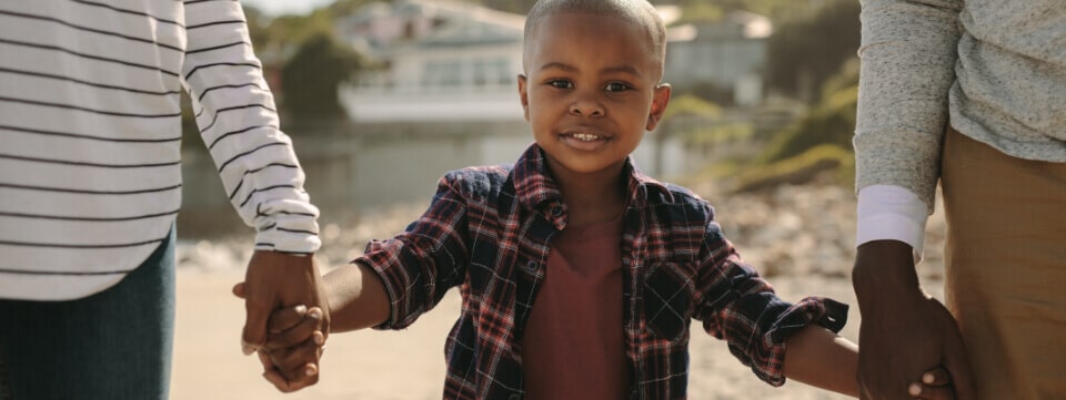 Young black child holding hands with parents
