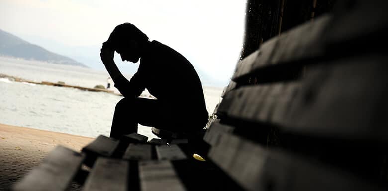 Man sitting alone on bench by the water
