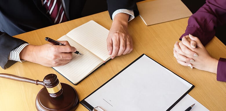Attorney meeting with female client, reviewing legal documents and taking notes