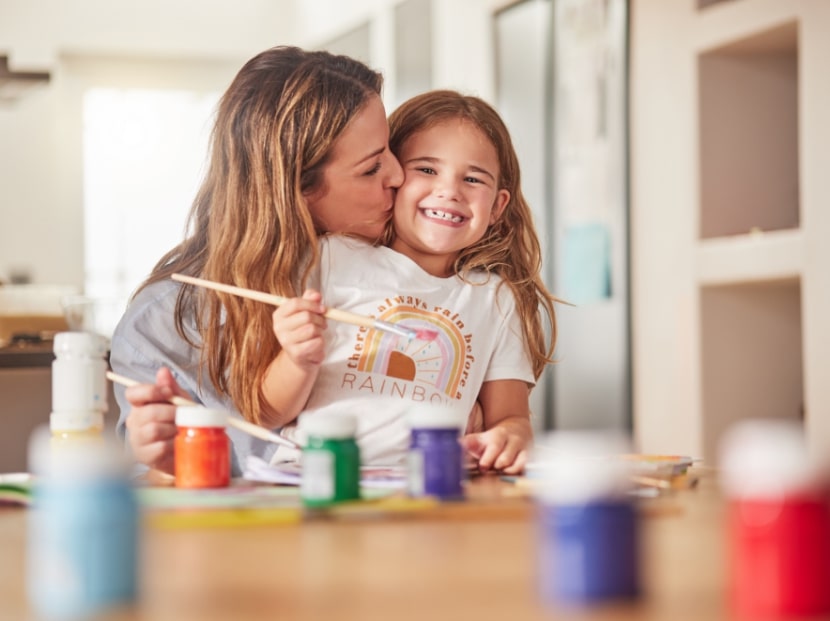 Foster care parent sitting at table with child painting