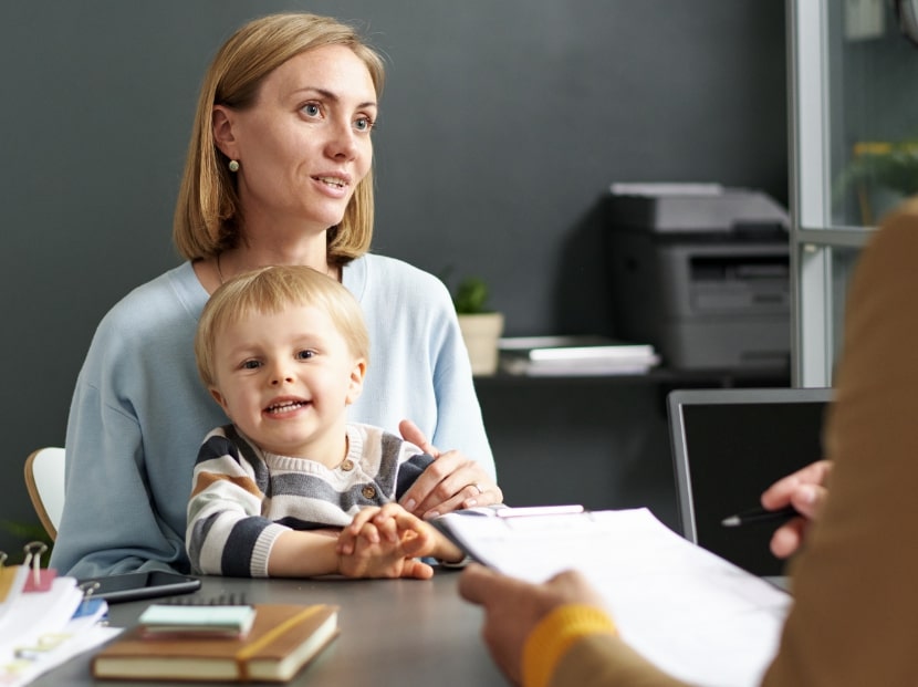 Mother sitting with child on her lap while talking to attorney